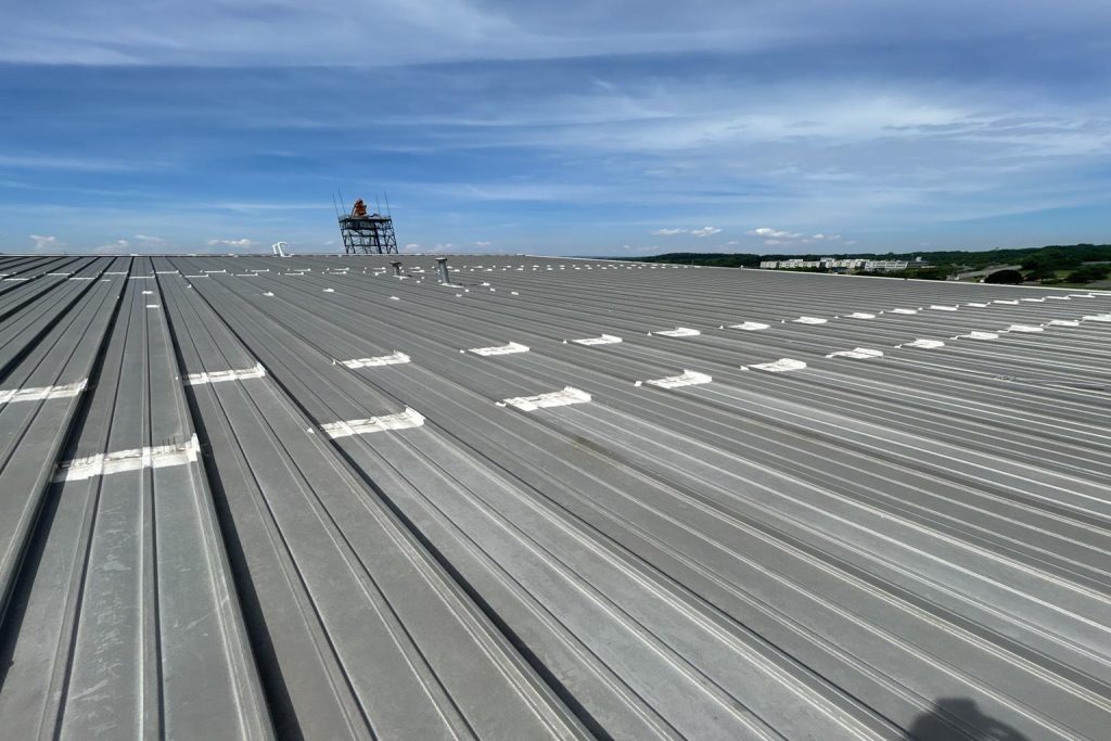 Industrial metal roof installation demonstrating durability and lifespan, answering "How long does a metal roof last?"
